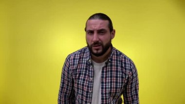 Orta yaşlı, sakallı, işitme zorluğu çeken bir adam, kameraya doğru eğilip başını sallıyor, anlaşmamızı ifade ediyor, sarı arka planda izole edilmiş kabul görüyor. Sb. Fısıltı zar zor duyuluyor.