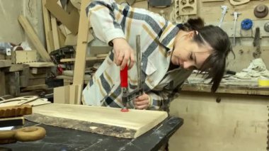Kadın katılımcı, marangozluk, ahşap atölye. Kapalı alanda ahşap aletlerle çalışan büyüleyici bir zanaatkar. Küçük bir iş. El yapımı üretim. Diy konsepti. Ekipman, arka plandaki malzemeler