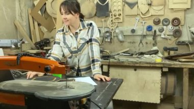 Kadın tasarımcı, marangozluk, ahşap atölye. Ev içinde çalışan, dizüstü bilgisayar kullanan çekici bir kadın. Küçük bir iş. El yapımı üretim. Diy konsepti. Ekipman, arka plandaki malzemeler
