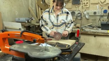 Kadın katılımcı, marangozluk, ahşap atölye. Kapalı alanda ahşap aletlerle çalışan büyüleyici bir zanaatkar. Küçük bir iş. El yapımı üretim. Diy konsepti. Ekipman, arka plandaki malzemeler