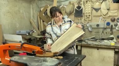 Kadın katılımcı, marangozluk, ahşap atölye. Kapalı alanda ahşap aletlerle çalışan büyüleyici bir zanaatkar. Küçük bir iş. El yapımı üretim. Diy konsepti. Ekipman, arka plandaki malzemeler