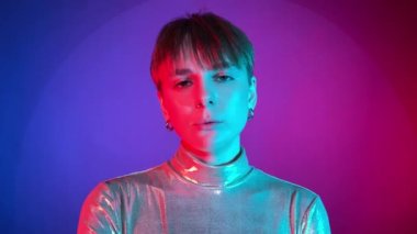 Portrait young adult woman having scornful look showing middle finger, fuck off expression, chewing gum in neon illumination indoors. Studio shot in art colorful lighting. Cyberpunk concept