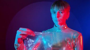 Tütünsüz konsept. Portre genç yetişkin kadın sigara koyuyor plastik torbaya neon aydınlatma kapalı mekanda. Sigara içme, bağımlılığı bırak. Parlak giysiler giyen kadın renkli ışıklandırma.