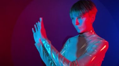 Sanal gerçeklik simülatöründe çalışan ve renkli neon ışığı üzerine hologram kontrol paneli dokunmatik ekranı uygulayan grafiksel kullanıcı arayüzü kullanan genç bir kadın portresi. Fütürist bilim kurgu konsepti kopyalama alanı