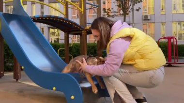 Küçük köpeği oynayan neşeli, genç bir kadın dışarıda eğleniyor. Sevimli kahverengi köpek evcil bir hayvana biniyor ve şehir parkında evcil bir hayvan yakalıyor. Arkaplanda binaların yerleşim alanı