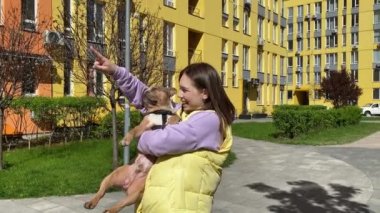 Neşeli, genç, yetişkin bir kadın bir şeyler gösteriyor. Güzel evcil hayvanına. Şehir köpeği konsepti. Sevecen evcil hayvan sahibi şehir parkında evcil hayvanlarla vakit geçirmekten hoşlanıyor.
