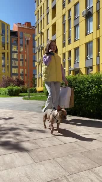 Anjing Berjalan Vertikal Wanita Muda Memegang Tas Belanja Berbicara Telepon — Stok Video