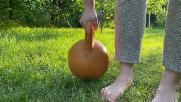 女人在日落时举起水壶铃 另一只手拿着轻量气球 平衡概念 比较两个物体 作为找到生活平衡的类比 背景公园 — 图库视频影像