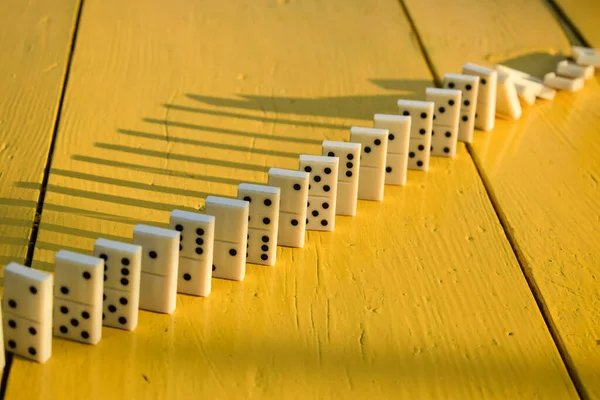 Domino taşları bilinmeyen birine dokunarak sarı masaya düşüyor. Sebep ve sonuç kavramı. Domino etkisi. Zincirleme reaksiyon, bir olayın neden olduğu olaylarla benzerlik gösterir
