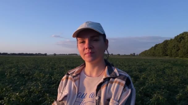 黄金の時間でカメラを見て肖像放射女性農家 暖かい光の中で日光浴農業風景 女性農学者は 視線を遠くに向ける夕日の美しさを受け入れる — ストック動画