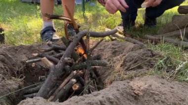 Baba ve çocuklar güneşli bir günde güzel bir ormanda kamp alanı kurdular. Baba kamp ateşi yakarken yakacak odunlara yaklaşıyoruz. Açık havada aile tatili. Bağ kurma, kamp, macera, yürüyüş