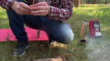 Baba kamp ateşinde şekerleme pişiriyor, kızıyla şeker paylaşıyor. Ailece güneşli bir günde ormanda kamp yaparken dışarıda yemek pişirmek. Kamp sandalyesinde oturan tatlı dudaklı bir kız.