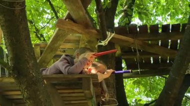 Merak dolu yakın çekim çocukları ağaç evde oynuyorlar. Çocuklar oyuncak dürbünden bakıp maceralı bir hayali yolculuğa çıkıyorlar. Kardeş bağı, neşe çocukluk keşfi ve fantezi