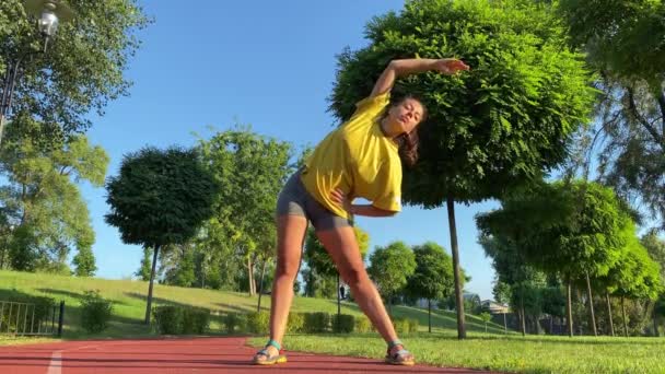 다인종 여자는 고요한 공원에서 운동을 합니다 그녀는 온난화 스트레칭 하늘과 — 비디오