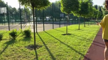 Arkadan bakıldığında çok ırklı genç bir kadın manzara manzaralı bir parkta sabah antrenmanına çıkıyor. İp atlayarak sınırsız enerji aşımı yapıyor. Açık mavi gökyüzü ve altın güneş ışığı. Etkin yaşam biçimi