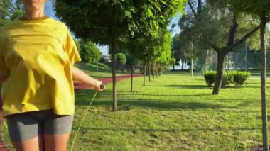 Coşkulu, çok ırklı bir genç kadın sabah sporunda çevre düzenlemesi yapılan parka gidiyor. İp atlayarak sınırsız enerji aşımı yapıyor. Açık mavi gökyüzü ve altın güneş ışığı. Etkin yaşam biçimi