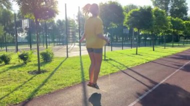 Coşkulu, çok ırklı bir genç kadın sabah sporunda çevre düzenlemesi yapılan parka gidiyor. İp atlayarak sınırsız enerji aşımı yapıyor. Açık mavi gökyüzü ve altın güneş ışığı. 360 derece video
