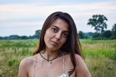 Huzurlu güzellikteki alacakaranlık çayırında, çok kültürlü genç bir kadın huzurlu bir ifadeyle büyülenir. Huzurlu bir sükunet, günün büyülü bir anında huzurlu bir çayırlık havasını tamamlar.