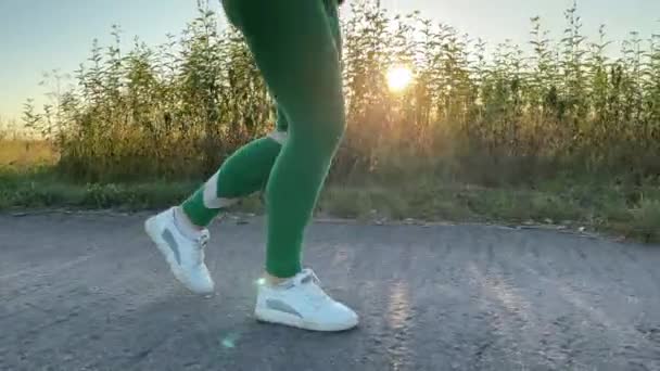 Eine Junge Frau Joggt Bei Sonnenuntergang Über Eine Landstraße Und — Stockvideo