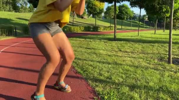 若い女性は 公共の公園で晴れた朝に激しい脚と太いトレーニングに出発します クローズアップ女性低セクションは 彼女が運動ルーチンで従事するように自然な筋肉の動きを示しています — ストック動画