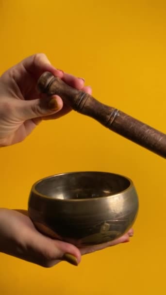 티베트 그릇을 몰렛을 사용하여 진동을 만듭니다 노란색 배경에 명상과 평온의 — 비디오