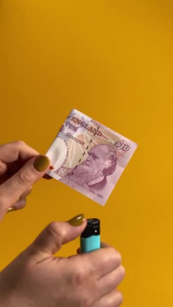 纸货币崩溃 货币替换 金融概念 一只雌性手拿着钞票 在室内优雅地烧着时 点燃了10磅钞票 在黄色或橙色背景下隔离的垂直视频 — 图库视频影像