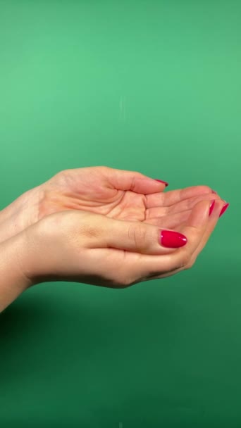 リフレッシュするアイデア ウェルネスビューティーコンセプト ピンクの爪を持つ認識できない女性は 純粋で清潔な水の流れをキャッチするために彼女の手をカップします 緑の背景に隔離された縦の屋内ショット — ストック動画