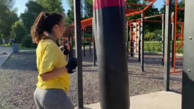Açık hava fitness eğitim alanında fiziksel aktivite. Çok ırklı genç bir kadın güneş doğarken halka açık bir parkta sabah antrenmanına çıkıyor. Güç, esneklik, refah kavramı