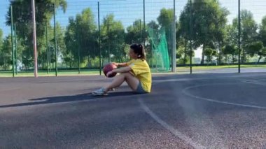 Aktif yaşam tarzı, halka açık spor salonunda tek başına basketbol antrenmanı. Genç çok ırklı bir kadın spor sahasında basketbol antrenmanı yapıyor. Güneşli bir günde açık hava aktiviteleri, sağlık ve refah kavramı
