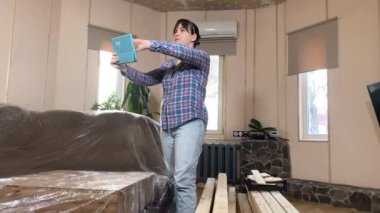 Evde tadilat yapan bir kadın, bina içi inşaat malzemelerinin yenilenmesi için hazırlık yapıyor. Yeniden yapılanma, DIY konsepti. Handywoman dijital tablet kullanarak yeniden modelleme planı