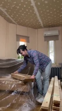Evde tadilat yapan genç bir kadın, içerideki inşaat malzemelerinin yenilenmesi için hazırlık yapıyor. Dikey çekim, DIY konsepti. Mobilya montajı yapan hizmetli kadın