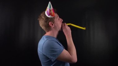 Gösterişli bir genç adam renkli bir parti şapkası takıyor, parlak gülüşü ve neşeli tavırları kutlama ruhunu en az siyah arkaplanda yakalıyor. Bulaşıcı bir yaşam sevinci ve kaygısız coşku.