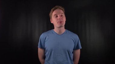 Çekici genç bir adam portre çekiminde duruyor, parlak siyah bir zemine yapıştırılmış sakız çiğniyor. Büyüleyici varlığı kendine güveni yayıyor ve sahneye zahmetsizce serin bir hava katıyor.