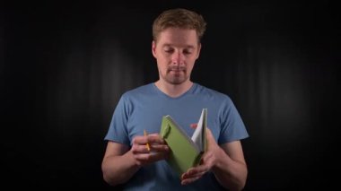 Elinde bir defter tutan yakışıklı beyaz bir adamın portresi, onu açıyor, notlar yazıyor, siyah bir arkaplanda bir planlamacıya giriş yapıyor. Amaçlı bir yaşam tarzında planlama ve kayıt tutma