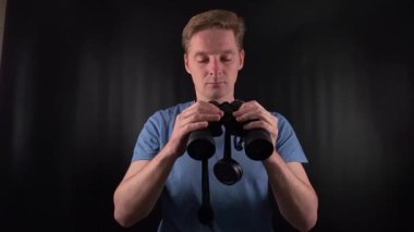 Niyetli bir genç adam siyah bir zemin üzerinde bir çift dürbünle ufku inceliyor. Merak ve bilinmeyeni keşfetme arzusu. Macera ve keşif ruhu