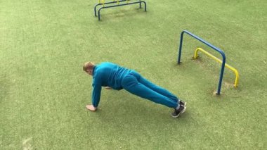 Odaklanmış genç bir atlet dinamik bir şekilde ısınma egzersizleri yapıyor ve dışarıda esniyor. Atletizm kıyafetlerini giyip titizlikle vücudu düzenli bir rutine göre fiziksel taleplere hazırlıyor.