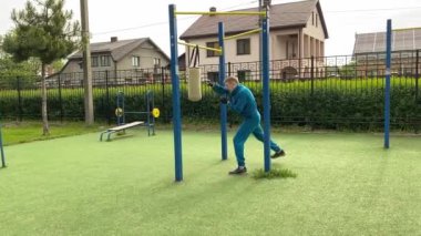 A dedicated young athlete puts in the hard work, vigorously training on gym equipment outdoors to prepare his body. He builds strength and endurance before hitting the field or court for competition