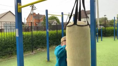 A dedicated young athlete puts in the hard work, vigorously training on gym equipment outdoors to prepare his body. He builds strength and endurance before hitting the field or court for competition