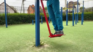 A dedicated young athlete puts in the hard work, vigorously training on gym equipment outdoors to prepare his body. He builds strength and endurance before hitting the field or court for competition