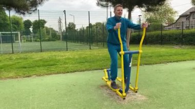 A dedicated young athlete puts in the hard work, vigorously training on gym equipment outdoors to prepare his body. He builds strength and endurance before hitting the field or court for competition
