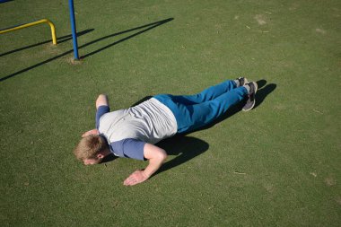 Odaklanmış genç bir atlet dinamik bir şekilde ısınma egzersizleri yapıyor ve dışarıda esniyor. Atletizm kıyafetlerini giyip titizlikle vücudu düzenli bir rutine göre fiziksel taleplere hazırlıyor.