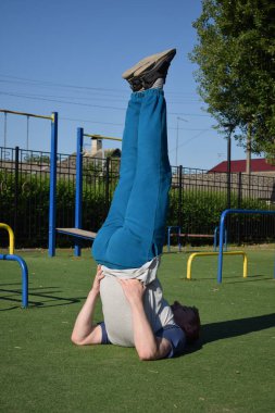 Odaklanmış genç bir atlet dinamik bir şekilde ısınma egzersizleri yapıyor ve dışarıda esniyor. Atletizm kıyafetlerini giyip titizlikle vücudu düzenli bir rutine göre fiziksel taleplere hazırlıyor.