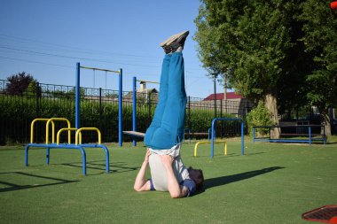Odaklanmış genç bir atlet dinamik bir şekilde ısınma egzersizleri yapıyor ve dışarıda esniyor. Atletizm kıyafetlerini giyip titizlikle vücudu düzenli bir rutine göre fiziksel taleplere hazırlıyor.