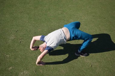 Odaklanmış genç bir atlet dinamik bir şekilde ısınma egzersizleri yapıyor ve dışarıda esniyor. Atletizm kıyafetlerini giyip titizlikle vücudu düzenli bir rutine göre fiziksel taleplere hazırlıyor.