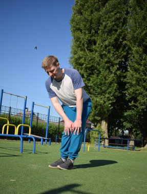 Odaklanmış genç bir atlet dinamik bir şekilde ısınma egzersizleri yapıyor ve dışarıda esniyor. Atletizm kıyafetlerini giyip titizlikle vücudu düzenli bir rutine göre fiziksel taleplere hazırlıyor.