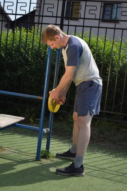 A dedicated young athlete puts in the hard work, vigorously training on gym equipment outdoors to prepare his body. He builds strength and endurance before hitting the field or court for competition
