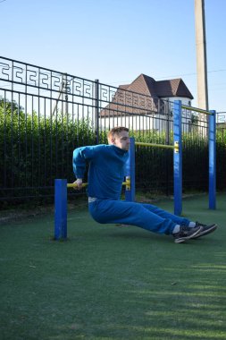 A dedicated young athlete puts in the hard work, vigorously training on gym equipment outdoors to prepare his body. He builds strength and endurance before hitting the field or court for competition