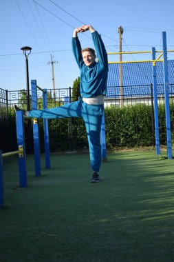 A dedicated young athlete puts in the hard work, vigorously training on gym equipment outdoors to prepare his body. He builds strength and endurance before hitting the field or court for competition