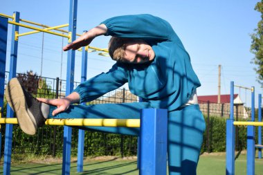 A dedicated young athlete puts in the hard work, vigorously training on gym equipment outdoors to prepare his body. He builds strength and endurance before hitting the field or court for competition