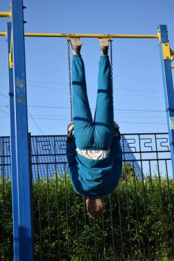 A dedicated young athlete puts in the hard work, vigorously training on gym equipment outdoors to prepare his body. He builds strength and endurance before hitting the field or court for competition